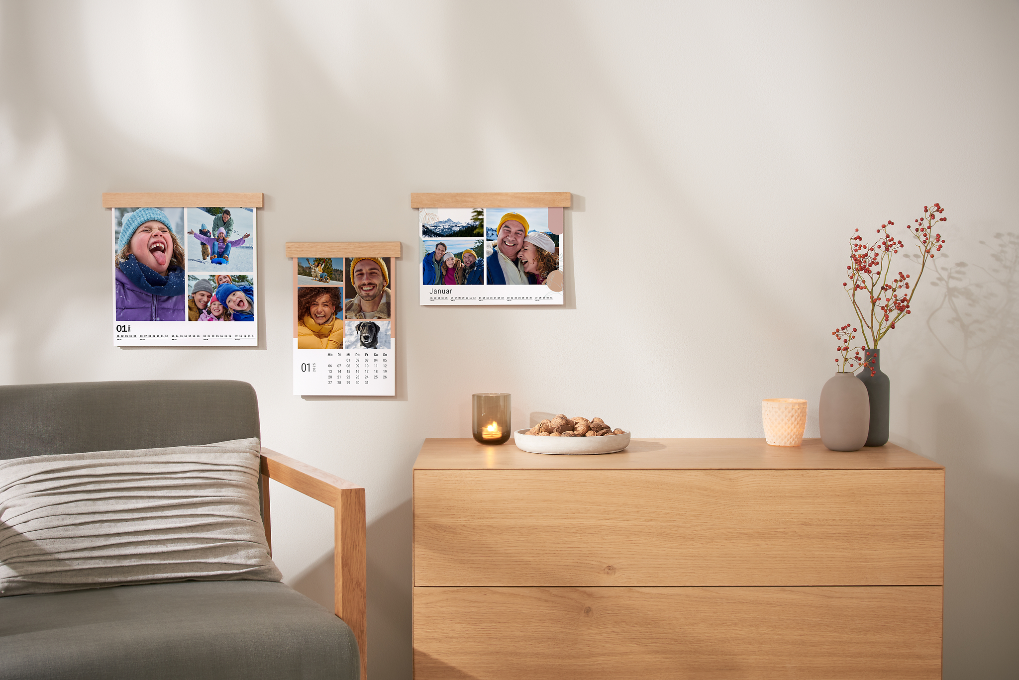 Drei Fotokalender mit einer dekorativen Holzleiste hängen an der Wand. Die Fotokalenderseiten sind alle mit Collagen aus mehreren Fotos gestaltet.