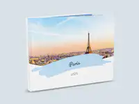 Fotobuch-Cover mit blau hinterlegtem Titel Ein aufgestelltes Reisefotobuch zeigt ein Cover mit dem Titel "Paris" und dem Untertitel "2026". Der Titel ist in blau hinterlegt. Das Cover zeigt ein Foto von Paris.