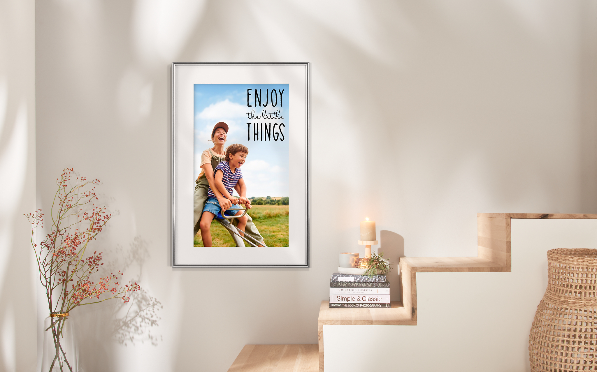 Ein Fotoposter hängt über einer Treppe mit dem Foto von einer Mama und ihrem Sohn. Auf dem gerahmten Poster steht der Spruch "Enjoy the little things".