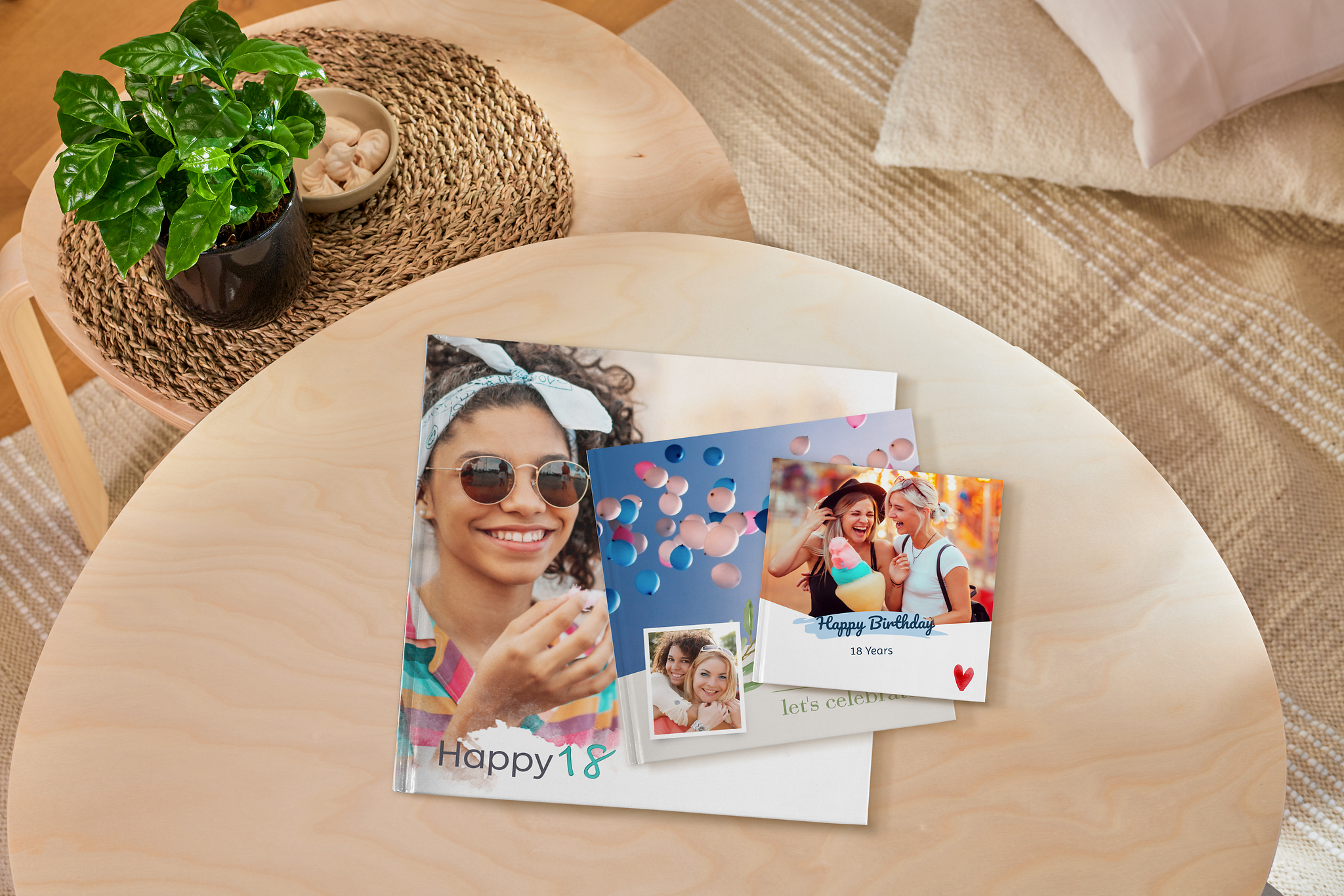 Drei Fotobücher als Geschenk zum 18. Geburtstag in verschiedenen Größen liegen auf einem Tisch.