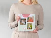 Großes Fotobuch als Babyalbum Ein als Babyalbum gestaltetes Fotobuch wird von einer Frau gehalten. Das Cover ist bunt mit mehreren Fotos gestaltet.