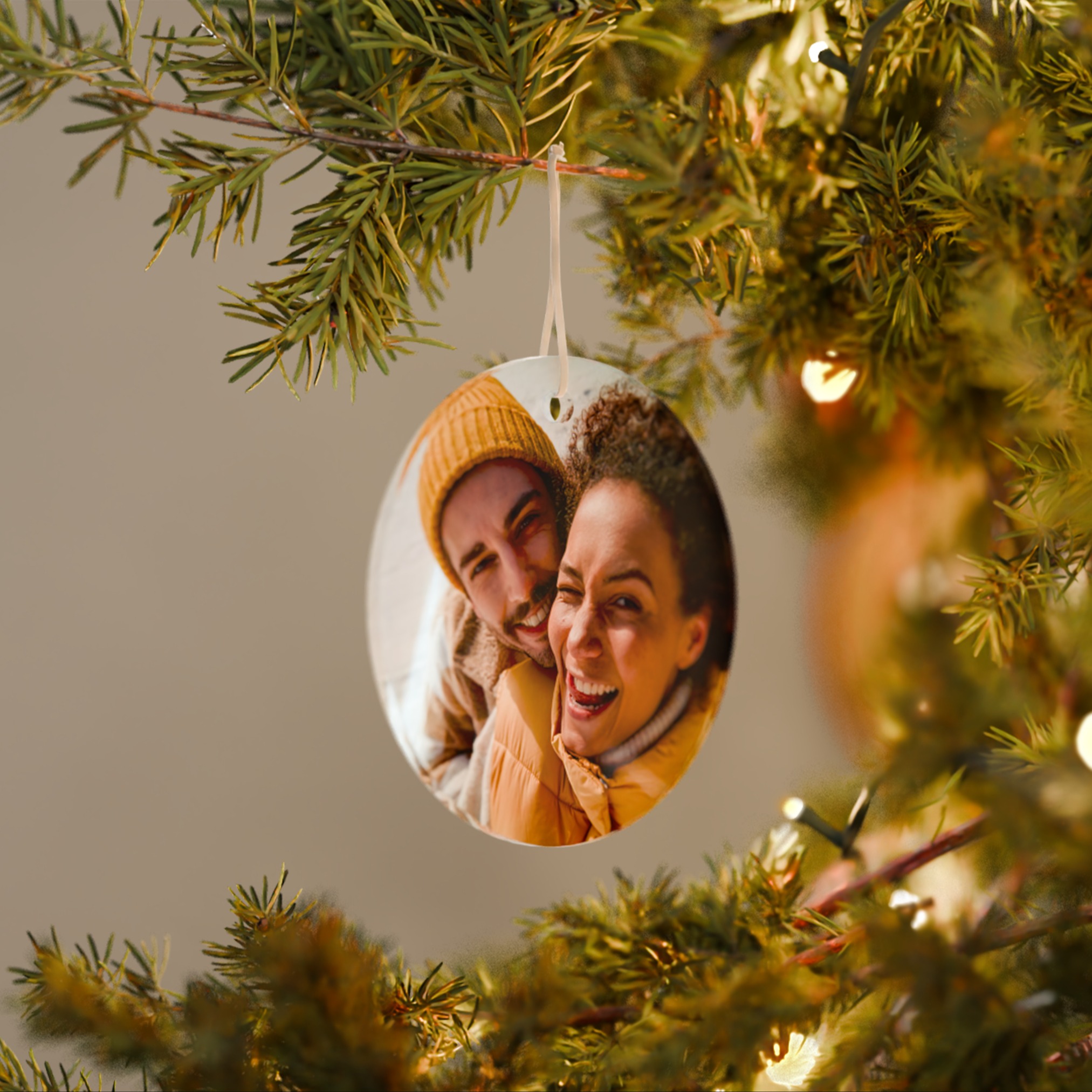 Foto-Weihnachtsanhänger mit einem Pärchenbild der mit einem Band an einem Tannenbaum befestigt ist. 