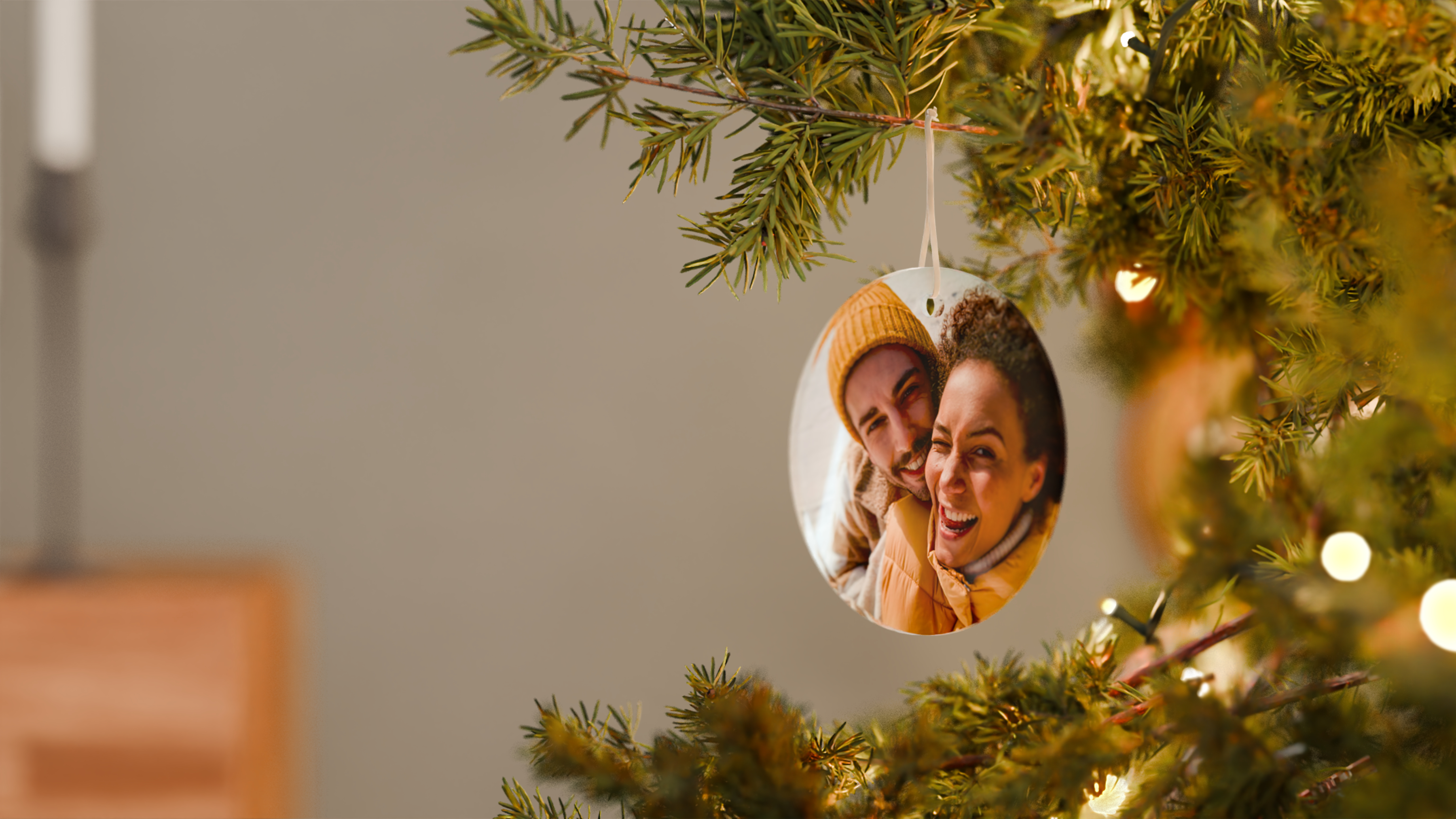 Foto-Weihnachtsanhänger mit einem Pärchenbild der mit einem Band an einem Tannenbaum befestigt ist. 