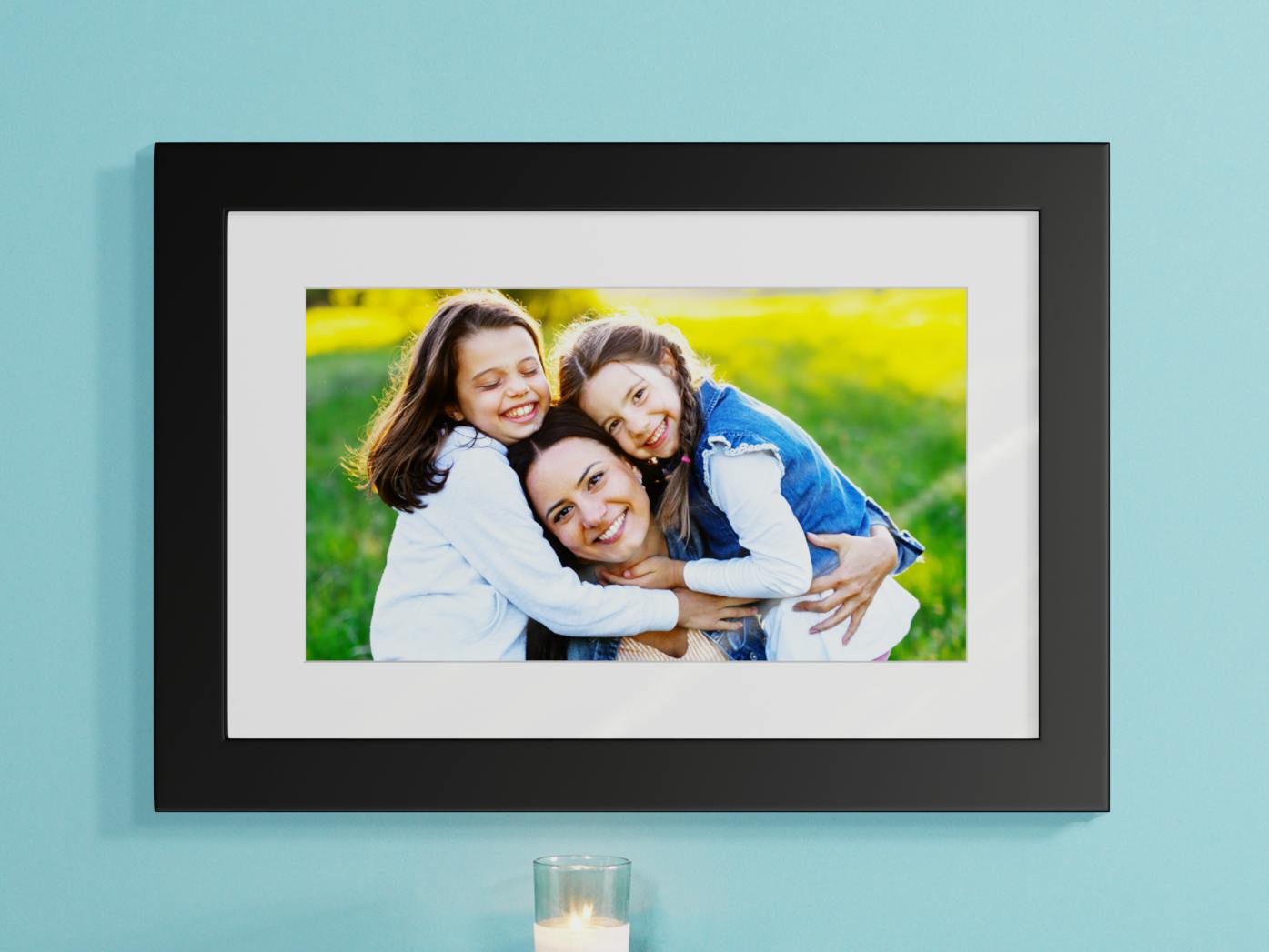 Foto einer lachenden Mutter mit ihren Töchtern im Grünen in einem schwarzen Bilderrahmen