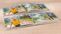 Fotoboek bindingen en papiersoorten Een fotoboek ligt open op een houten tafel, met vrolijke foto's van een kind in een gele jas naast een meer in de bergen.