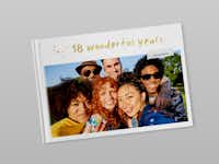 Fotobuch zum 18. Geburtstag Ein zugeklapptes Fotobuch mit dem Titel "18 wonderful years" und dem Foto einer Freundesgruppe. Der Titel ist in gold-glänzender Schrift veredelt.
