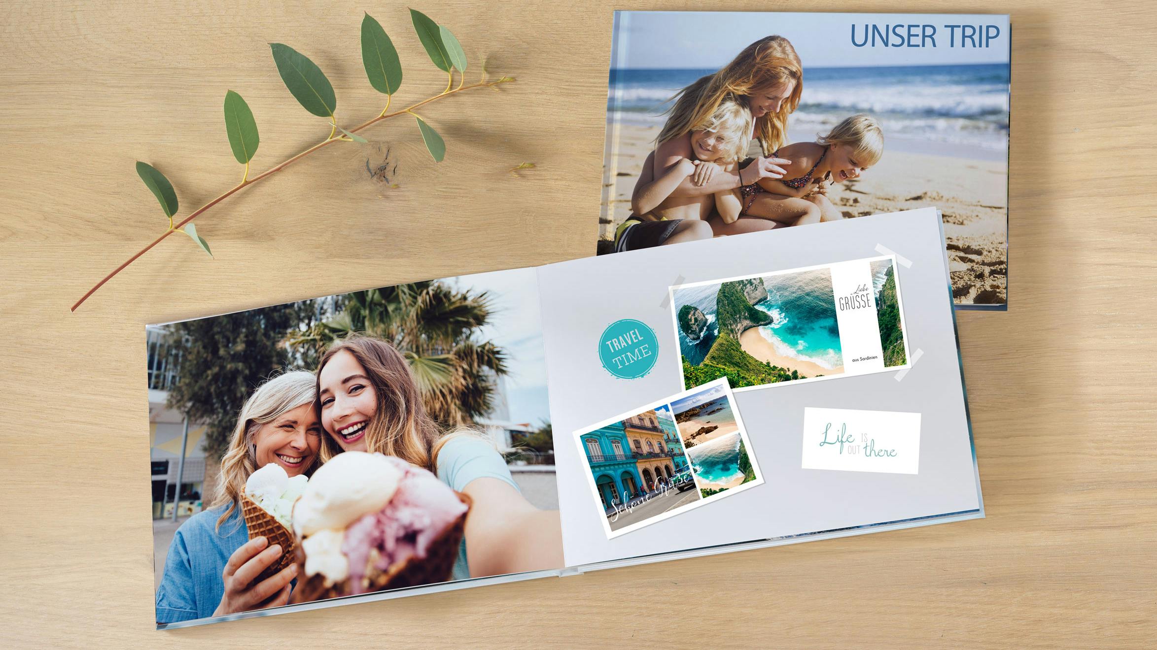 Aufgeschlagenes Fotobuch im Querformat mit sommerlichen Motiven und Postkarten-Designs auf einem Holztisch