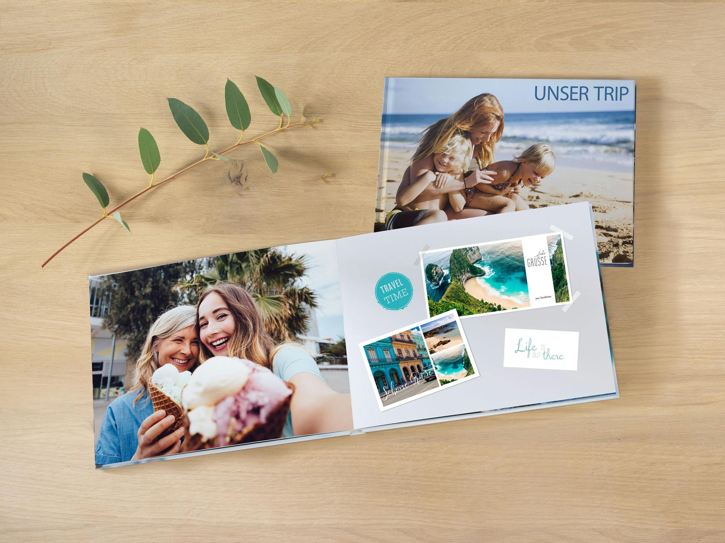 Opengeslagen fotoboek in liggend formaat met zomerse foto's en wenskaarten designs op een houten tafel