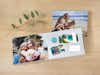 Opengeslagen fotoboek in liggend formaat met zomerse foto's en wenskaarten designs op een houten tafel