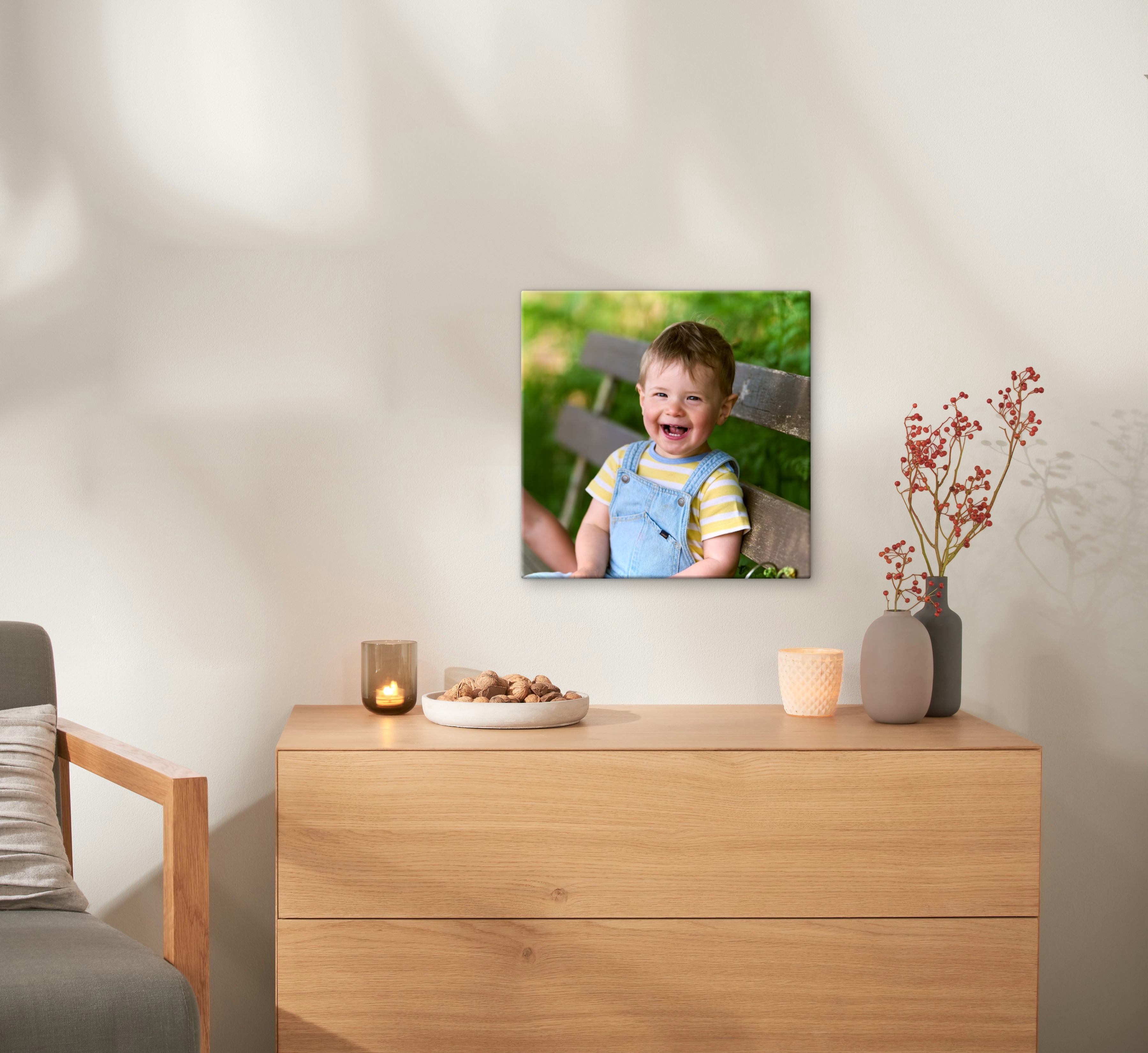 Eine Fotoleinwand im Format 40x40 cm hängt an einer Wand und zeigt ein Foto von einem lachenden Kleinkind.