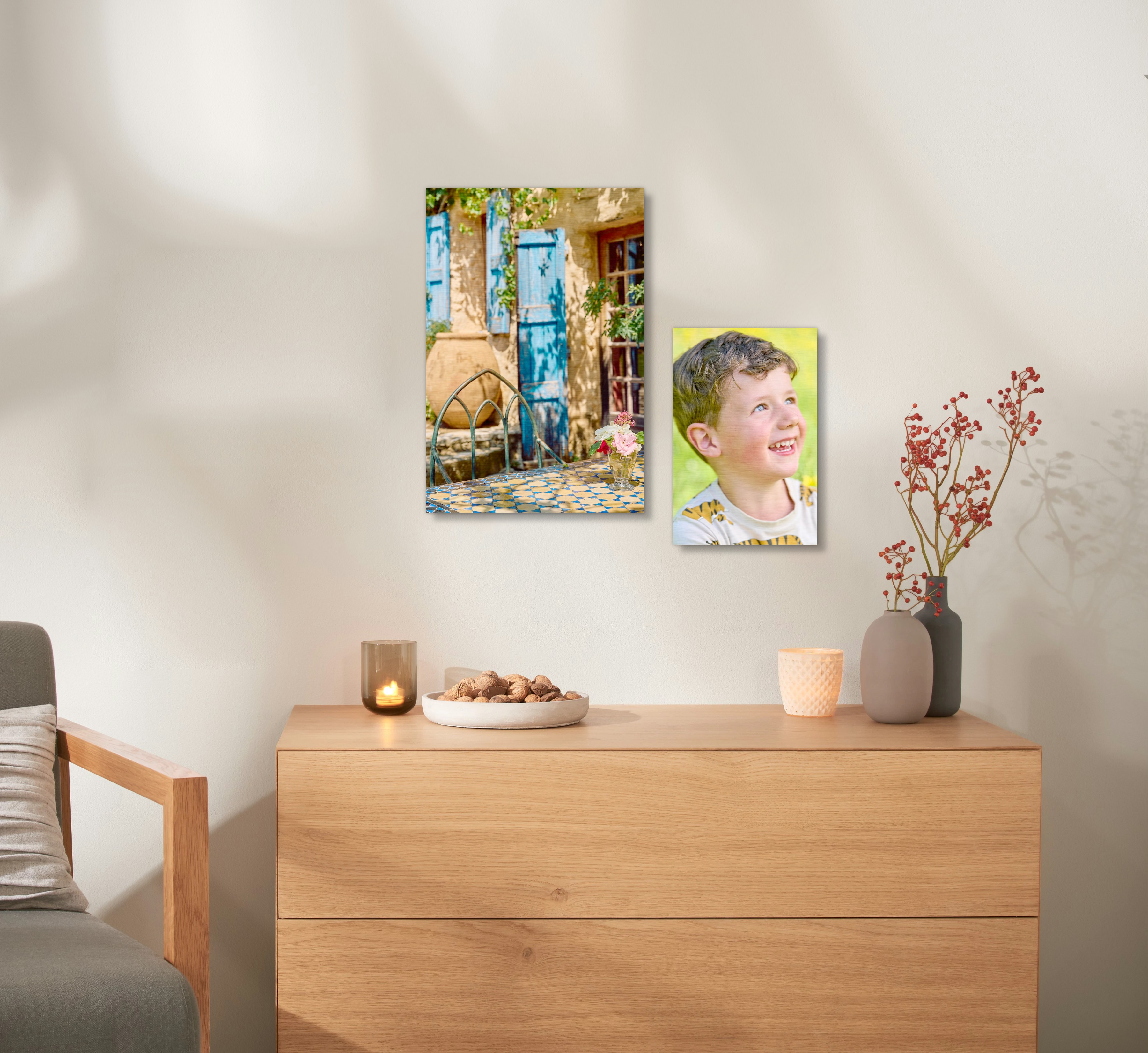 Ein Wandbild aus Holz mit einem Urlaubsfoto hängt an einer Wand, über einer Kommode. 