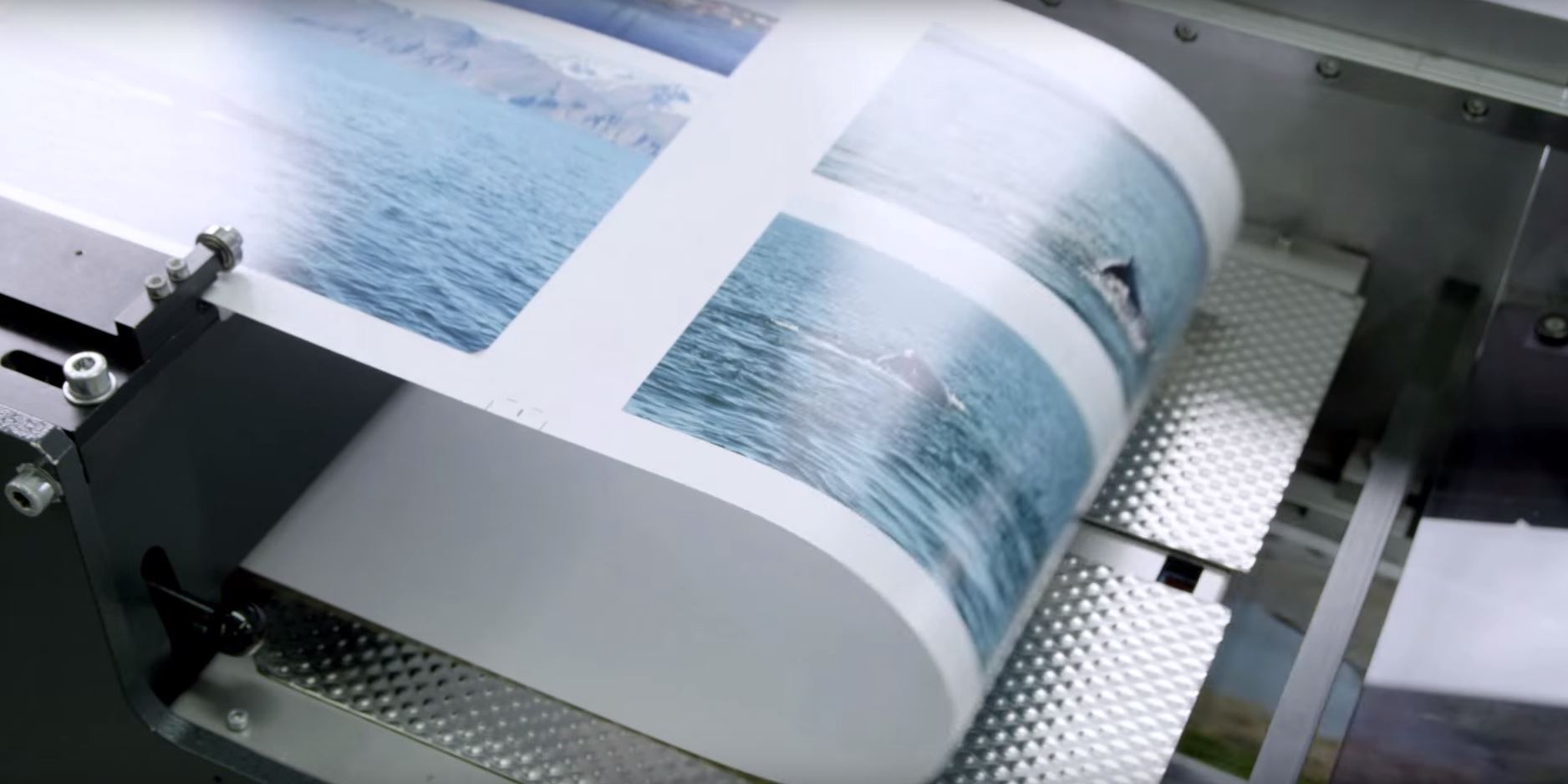 Een printer drukt een reeks foto's van een blauwe oceaan en bergen af op een vel papier.
