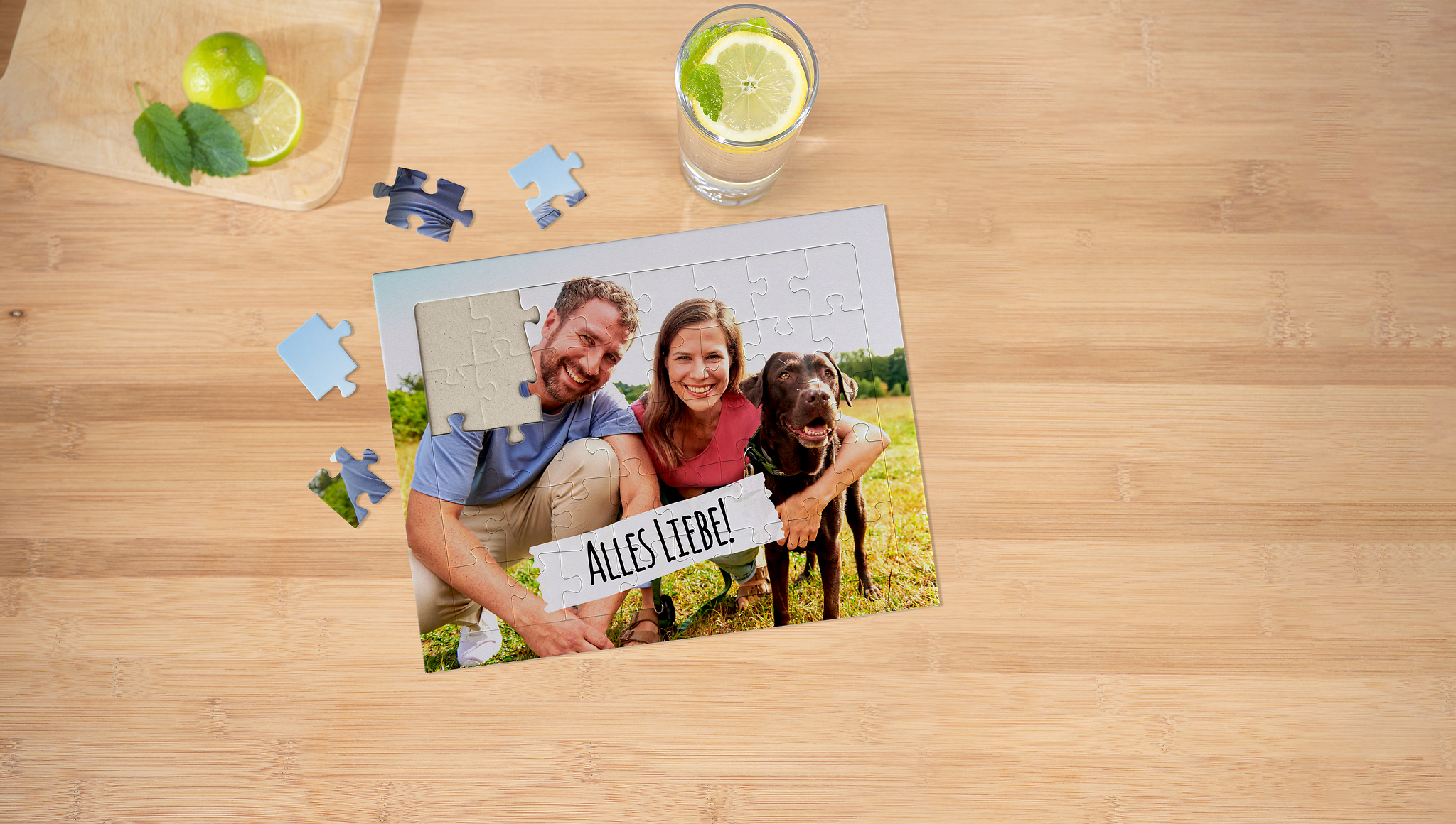 Fotopuzzle für Kinder. Das Motiv zeigt einen Hund und zwei Personen auf einer Wiese.