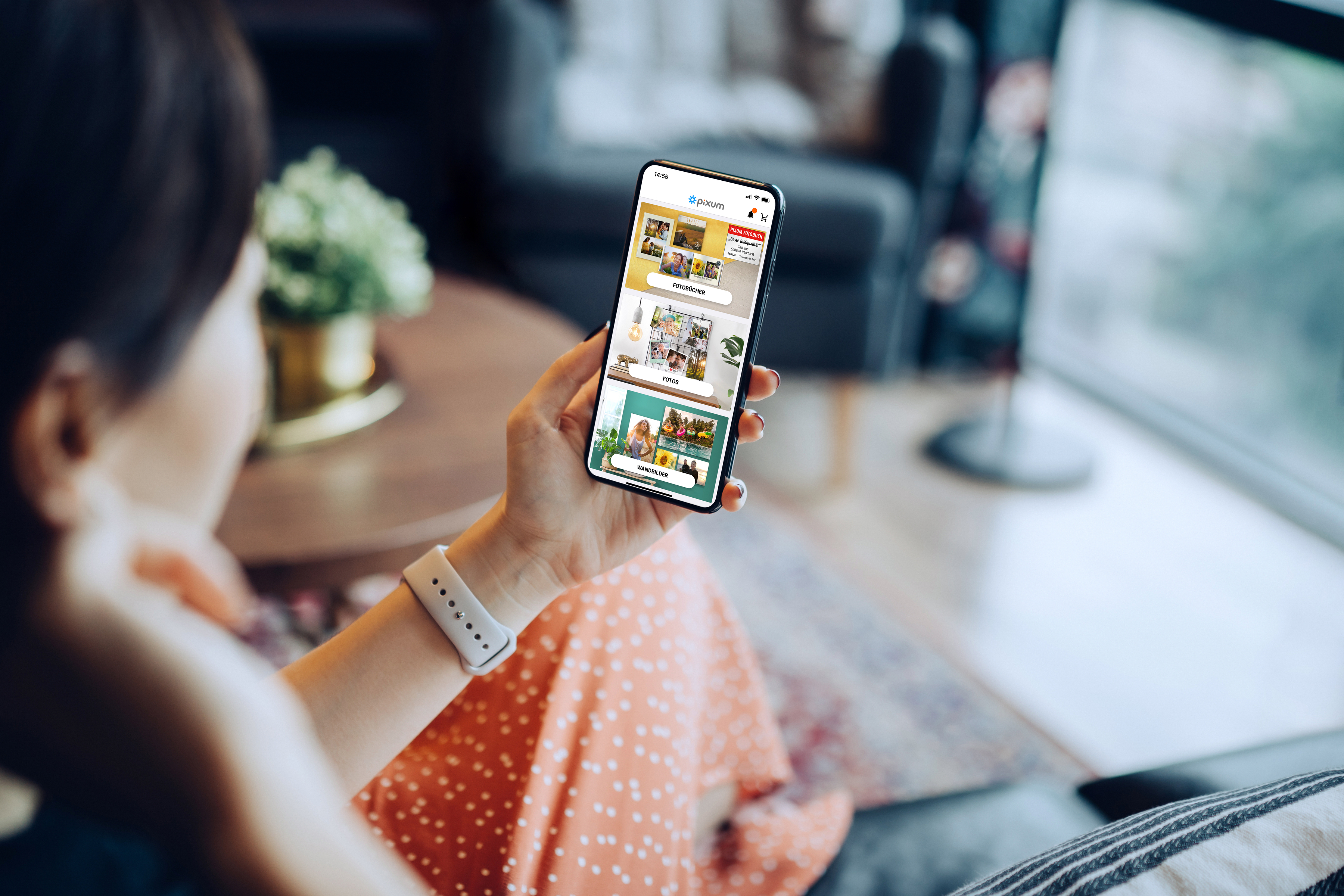 Frau, die ein Handy in der Hand hält, auf dem die Pixum App zu sehen ist