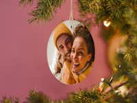 Foto-Weihnachtsanhänger mit einem Pärchenbild Foto-Weihnachtsanhänger mit einem Pärchenbild der mit einem Band an einem Tannenbaum befestigt ist.