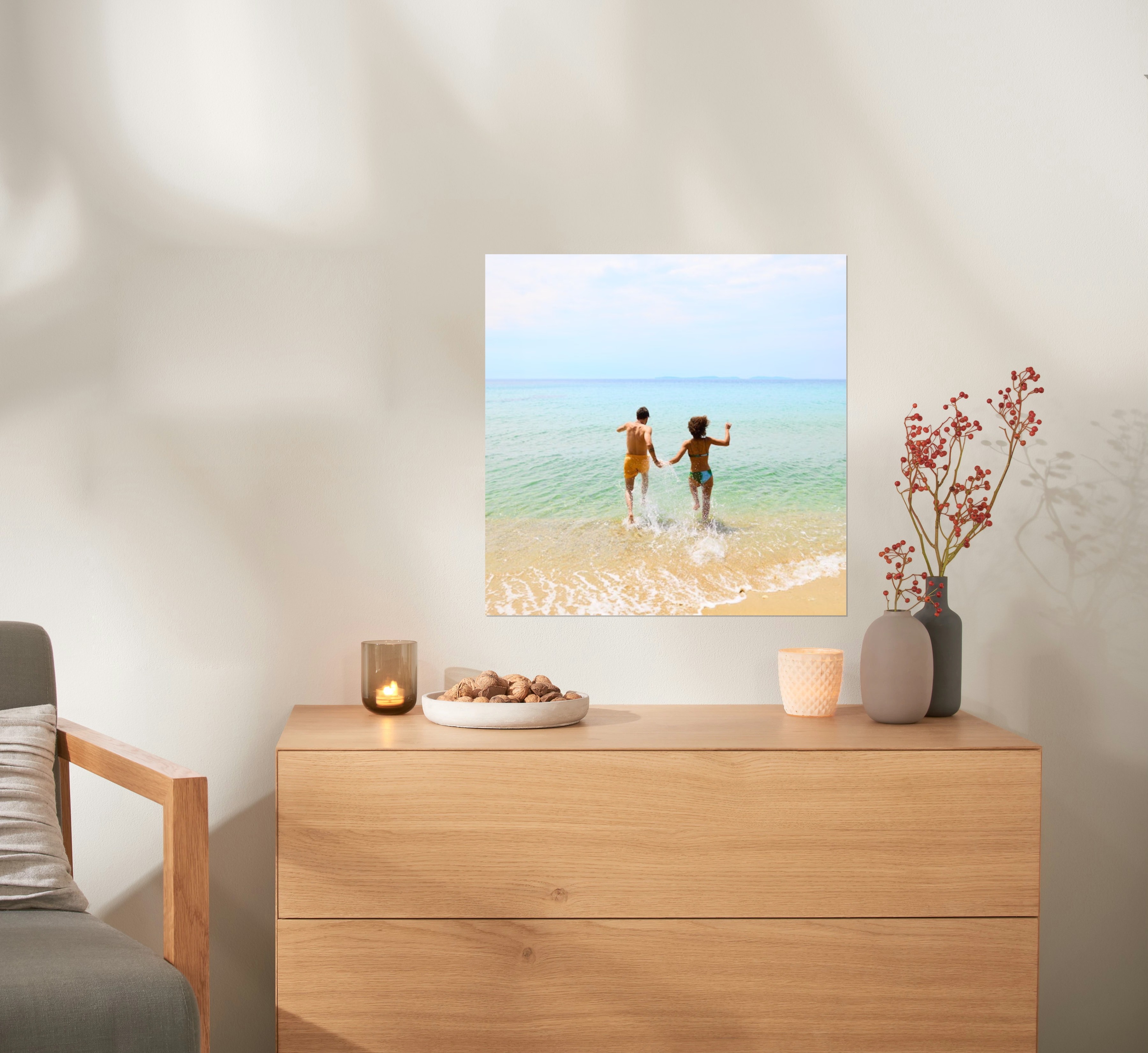 Ein Fotoposter im Format 50x50 cm hängt über einer Kommode und zeigt ein Pärchen am Strand