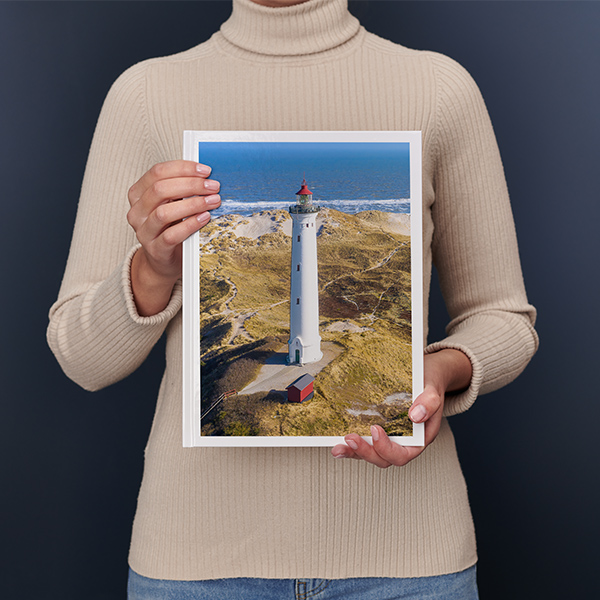 En kvinde holder en stor fotobog i højformat med et stort landskab i sine hænder