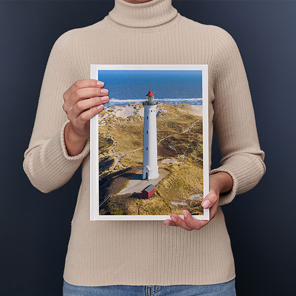 Una donna regge un Fotolibro Pixum grande verticale