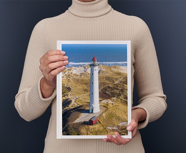 Una donna regge un Fotolibro Pixum grande verticale