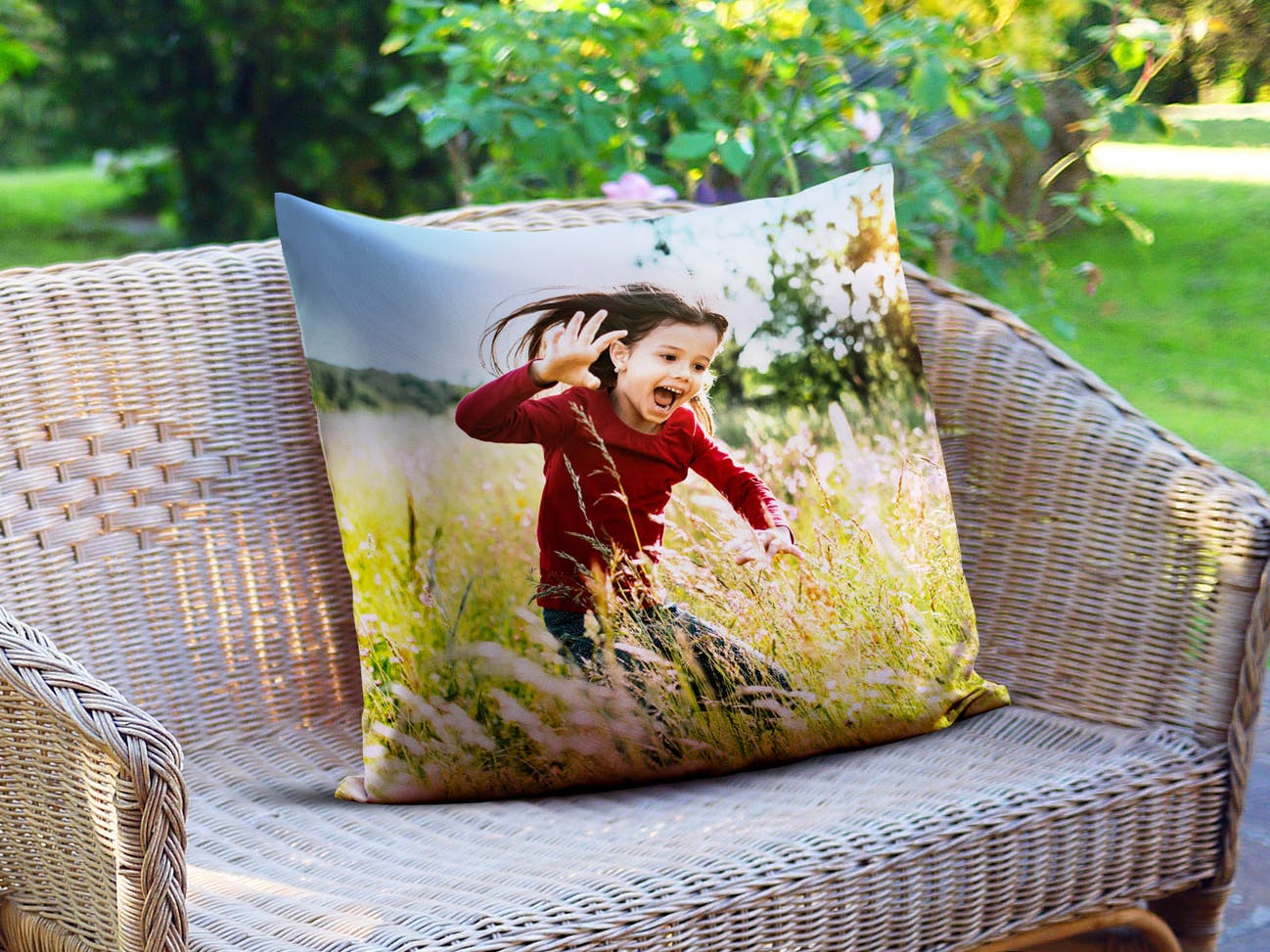 Cojín personalizado cuadrado en un banco de jardín con fotos de una niña que ríe