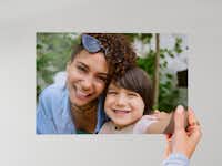 Fotoabzug 20 cm Hand, die einen 20 cm Fotoabzug vor einem neutralen Hintergrund hält, mit einem Familienfoto.