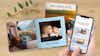 Pixum Fotobuch im quadratischen Format mit Familien- und Campingbildern, im Vordergrund ein Handy mit der Magicbooks-Funktion der Pixum App