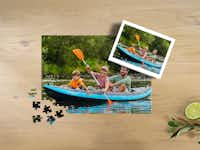 Fotopuzzle mit 200 Teilen und einem Bild von einer Familie beim Kanu fahren Fotopuzzle mit 200 Teilen und einem Bild von einer Familie beim Kanu fahren, aufliegend auf einem Tisch, inklusive einer Box für das Puzzle