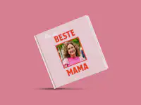 Fotobuch zum Muttertag gestalten Eine Person hält ein Fotobuch in der Hand. Dieses ist mit rosafarbenen Elementen zum Muttertag gestaltet.