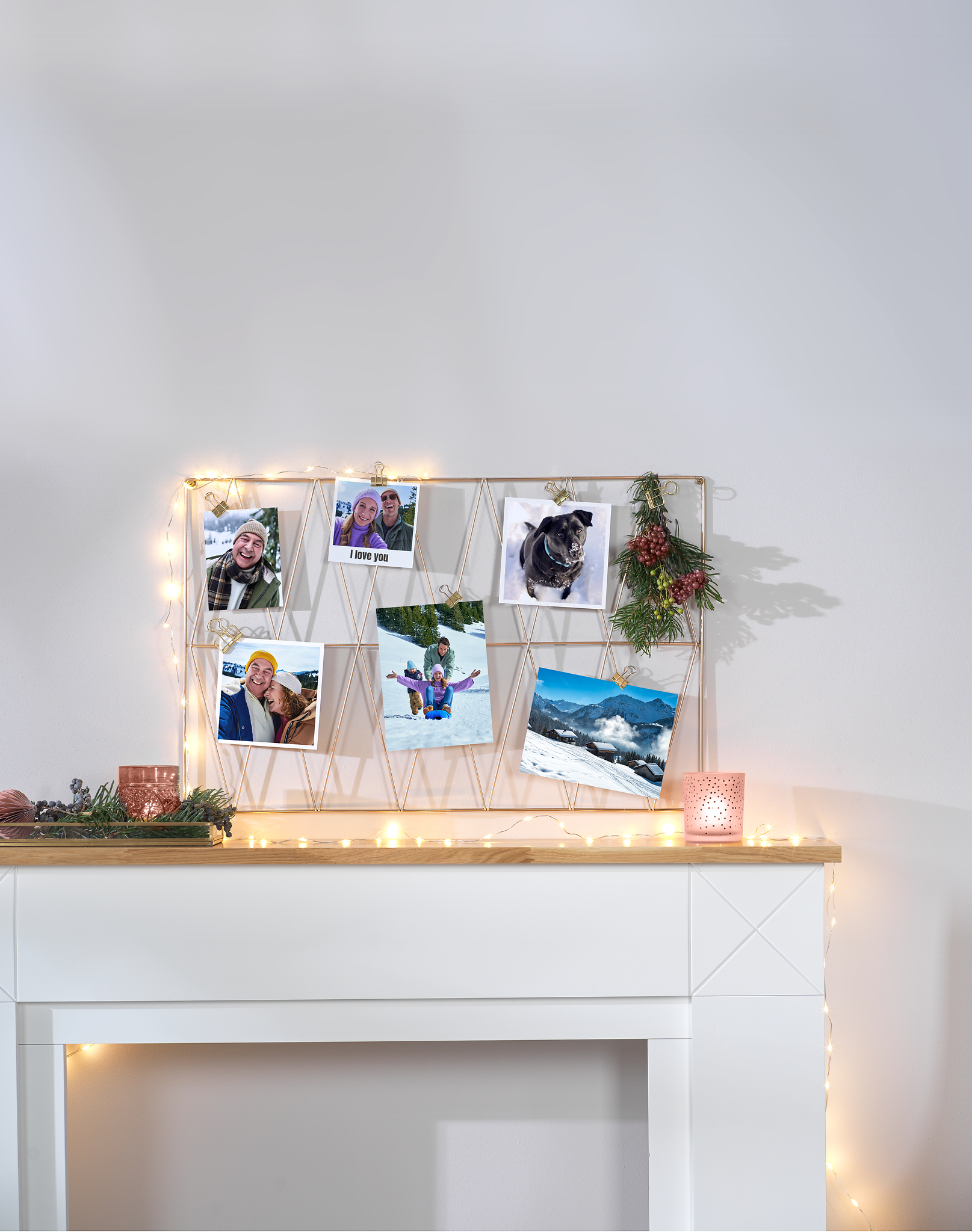 Een bord met fotoafdrukken van de winter en een lichtketting hangen aan de muur.