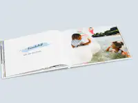 Fotobuch mit einem Kindheitsfoto von zwei Freund:innen Aufgeschlagenes Fotobuch mit einem Kindheitsfoto von zwei Freund:innen auf der rechten Seite und dem Text "Freunde seit der Kindheit" auf der linken Seite.