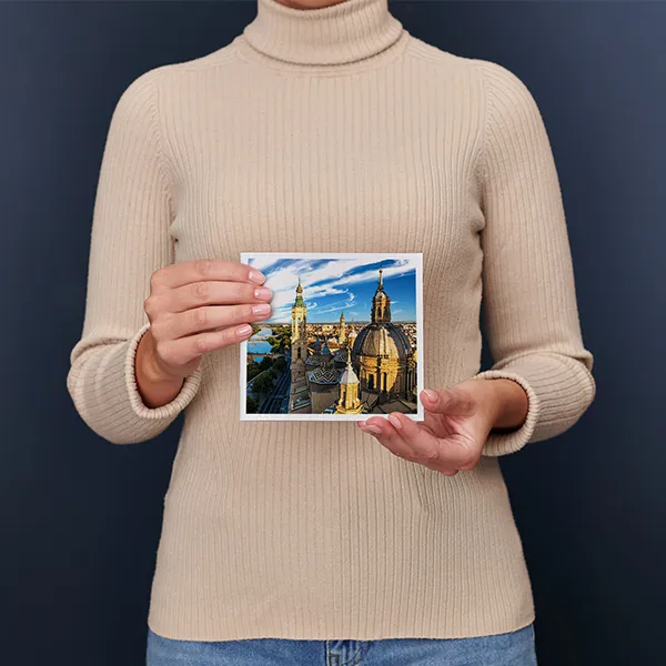 Una donna regge un Fotolibro Pixum piccolo quadrato