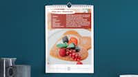 Rezeptkalender selbst gestalten Fotokalender im Hochformat mit einem Rezept für Pfannkuchen vor einer dunkelblauen Wand