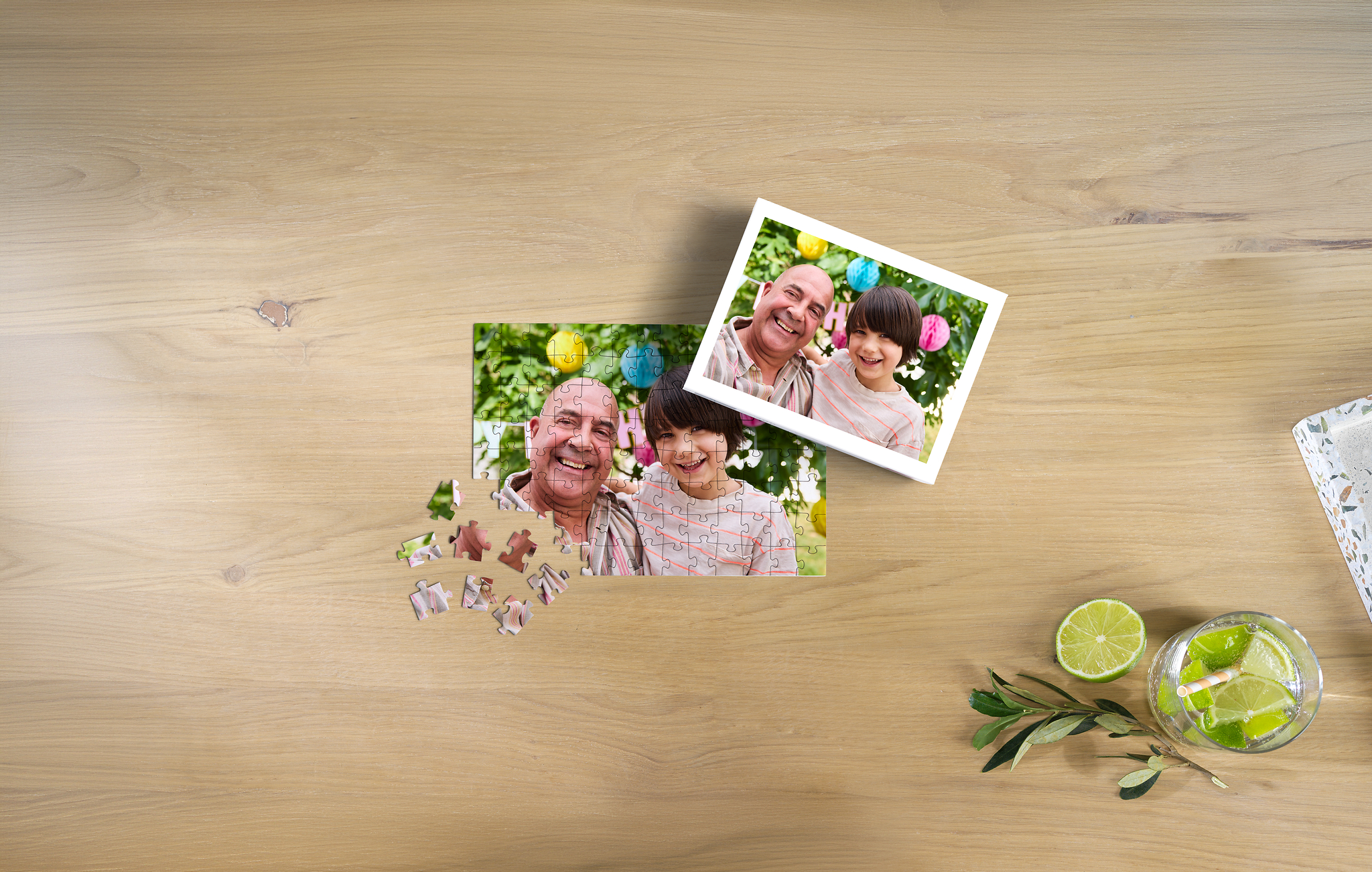 Puzzle personalizado de 100 piezas con la foto de un abuelo y su nieto con la caja del puzzle al lado sobre una mesa de madera