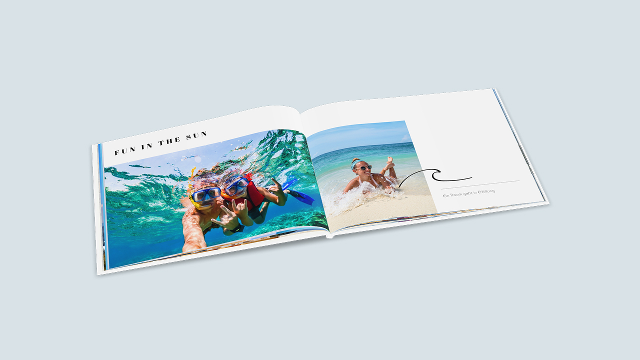 Aufgeklapptes Fotobuch mit Urlaubsbildern vom Tauchen und vom Strand. Die linke Seite ist mit dem Spruch "Fun in the Sun" verziert, die rechte Seite mit einer kleinen Zeichnung einer Welle und der Bildbeschriftung "Ein Traum geht in Erfüllung".