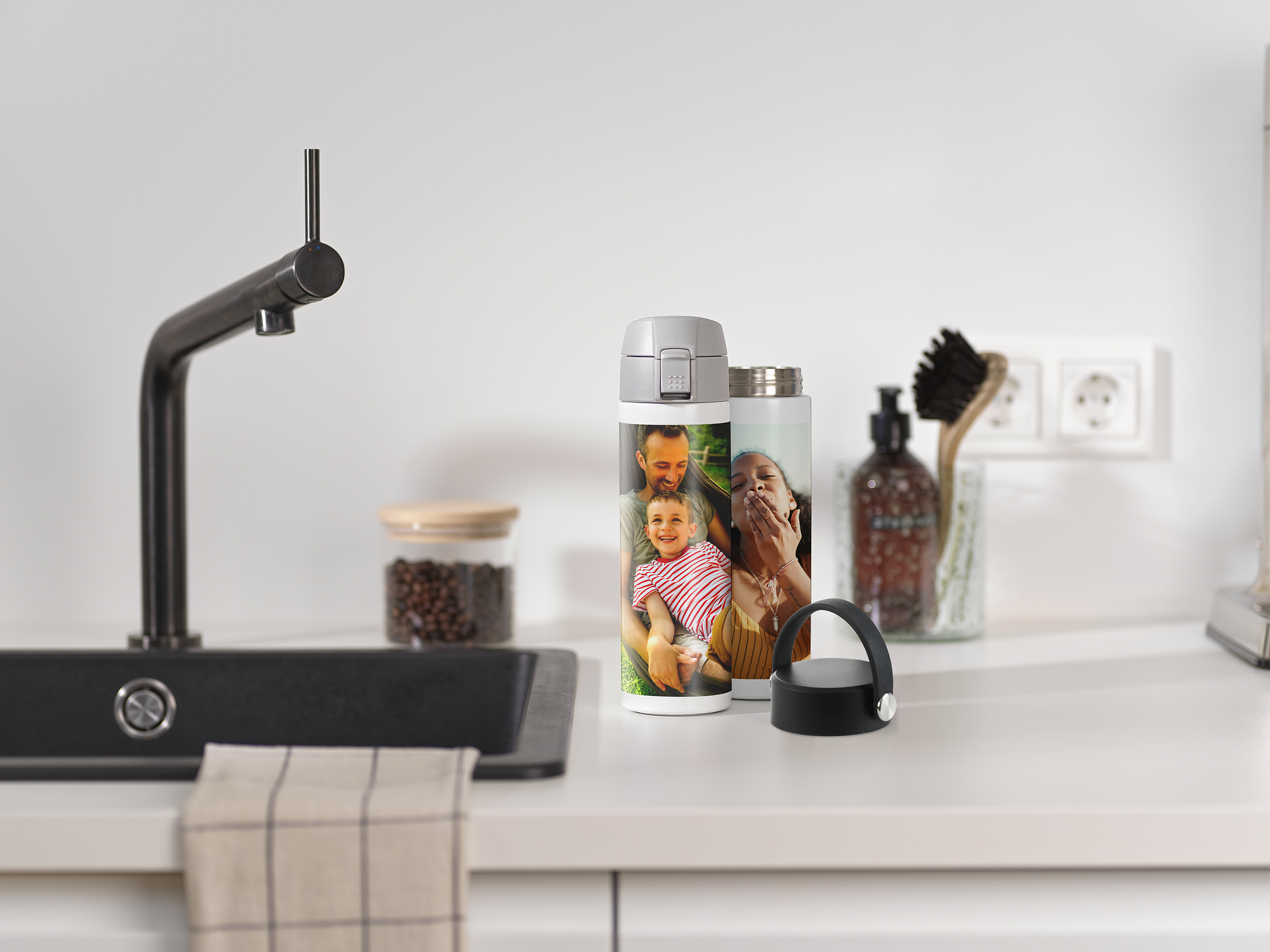 Een thermosfles met familiefoto's staat op een keukenaanrecht.