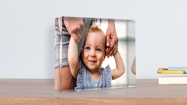 Glasfoto selbst gestalten Glasfoto mit Babymotiv auf einer Kommode.