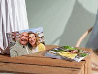 Fotoabzüge aus 100% recyceltem Material mit Fotos von einem Ehepaar Fotoabzüge aus 100% recyceltem Material mit Fotos von einem Ehepaar aufliegend auf einer Holzkiste