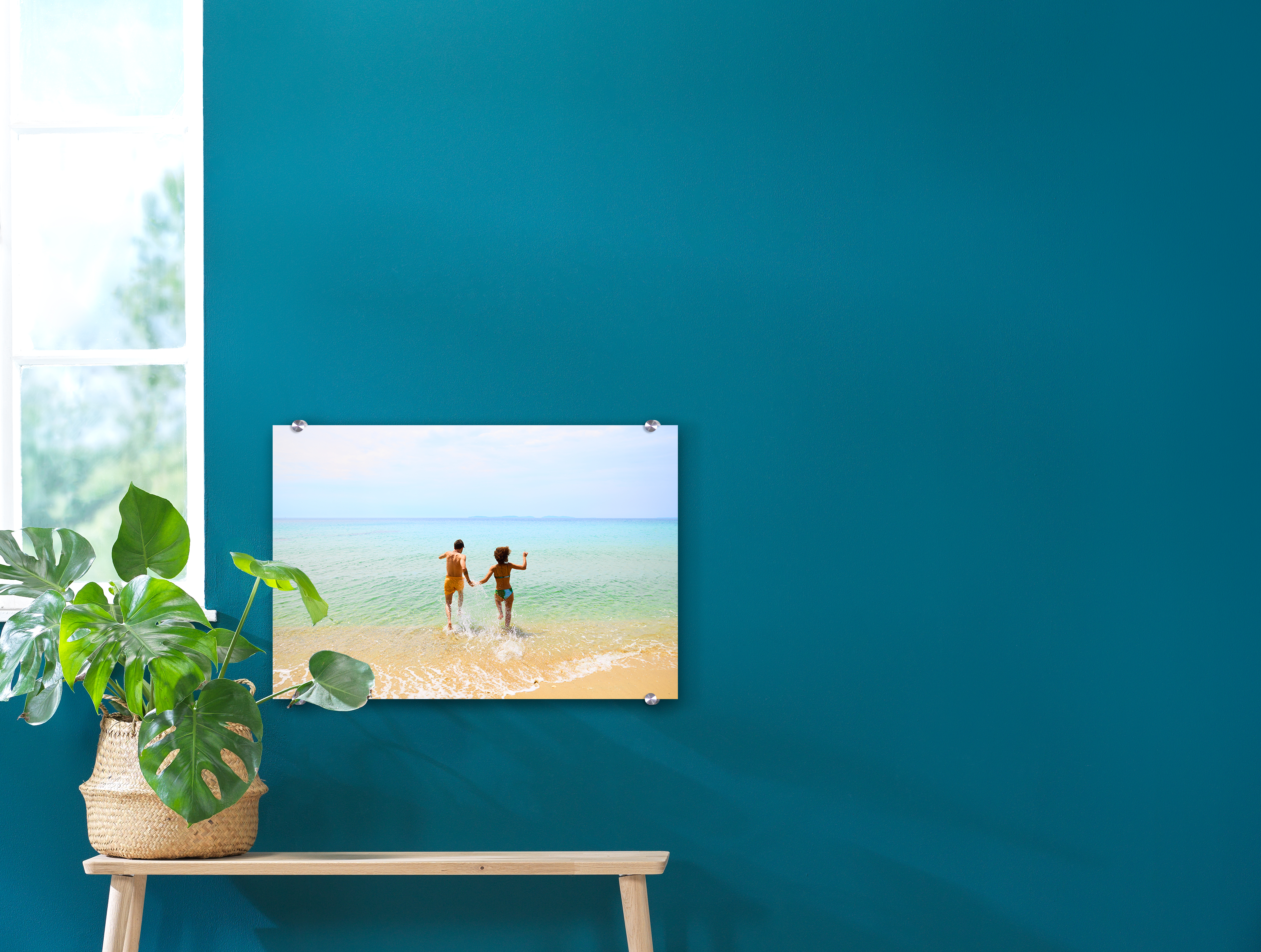 Foto hinter Acrylglas mit einem Strandfoto an einer blauen Wand