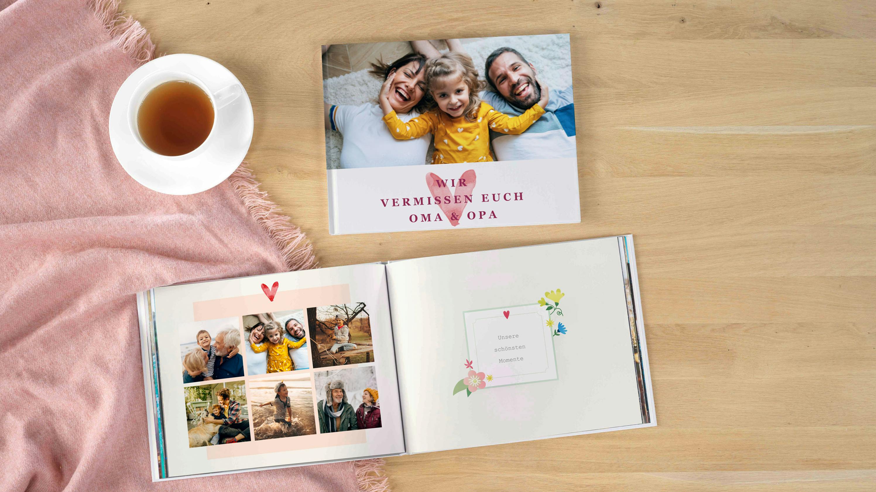 Fotobucheinband und aufgeklapptes Fotobuch mit Familienmotiven der Großeltern und Enkel auf einem Holztisch liegend