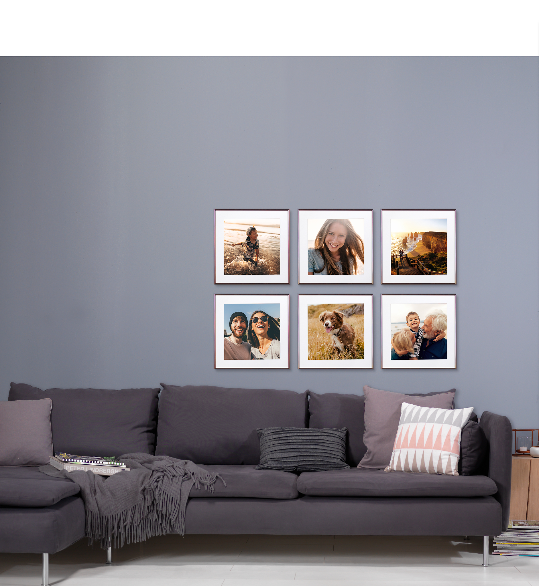 Das Bild zeigt eine Fotowand in Rasterhängung mit Familienbildern über einem Sofa.