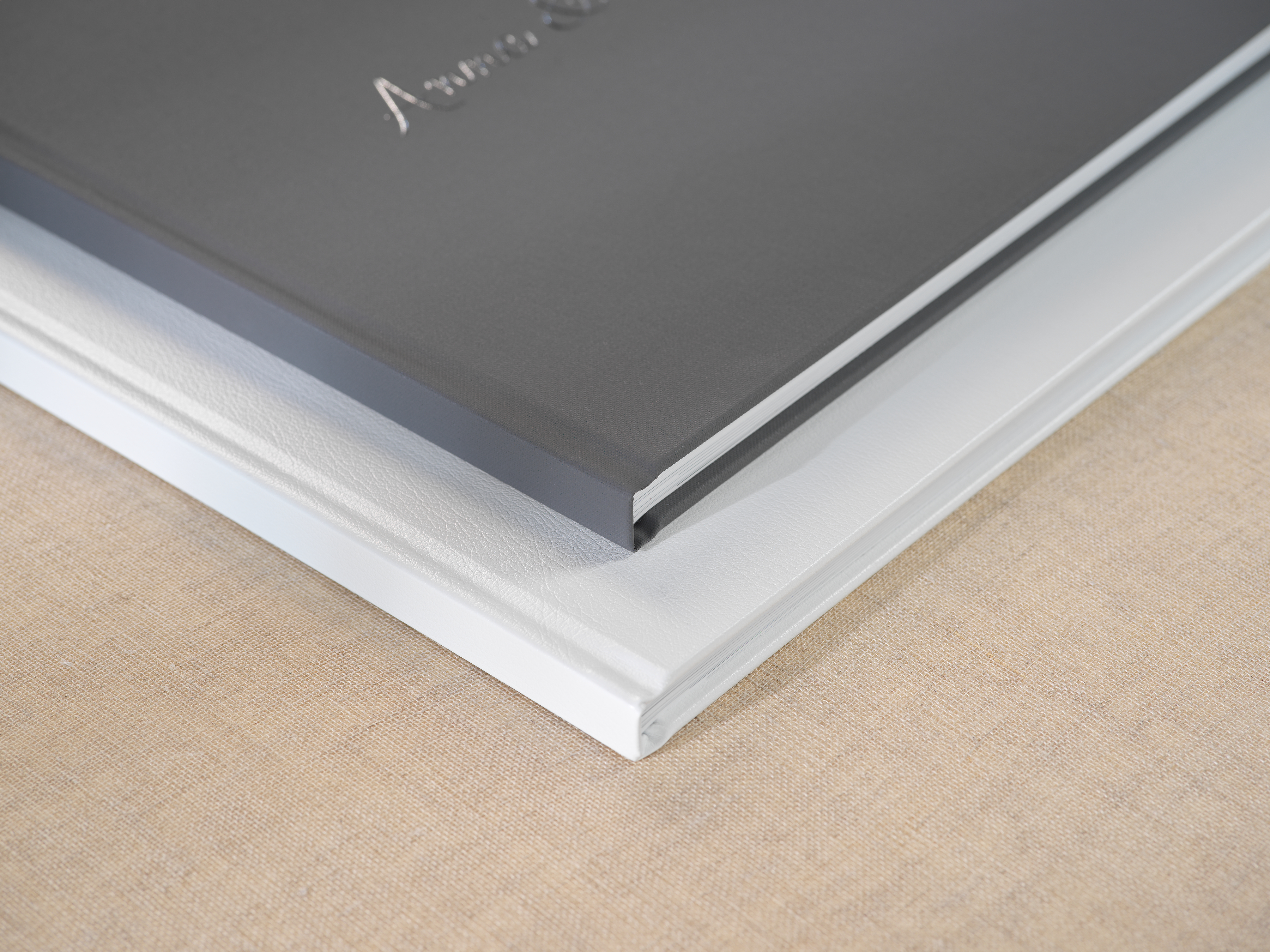 Detailopname van twee linnen fotoboeken die op elkaar gestapeld liggen.