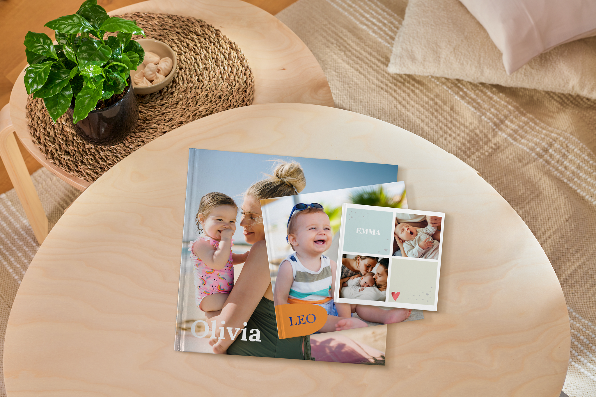 Drei Fotobücher in verschiedenen Größen liegen auf einem Tisch. Sie sind mit Designvorlagen erstellt und zeigen Babybilder.