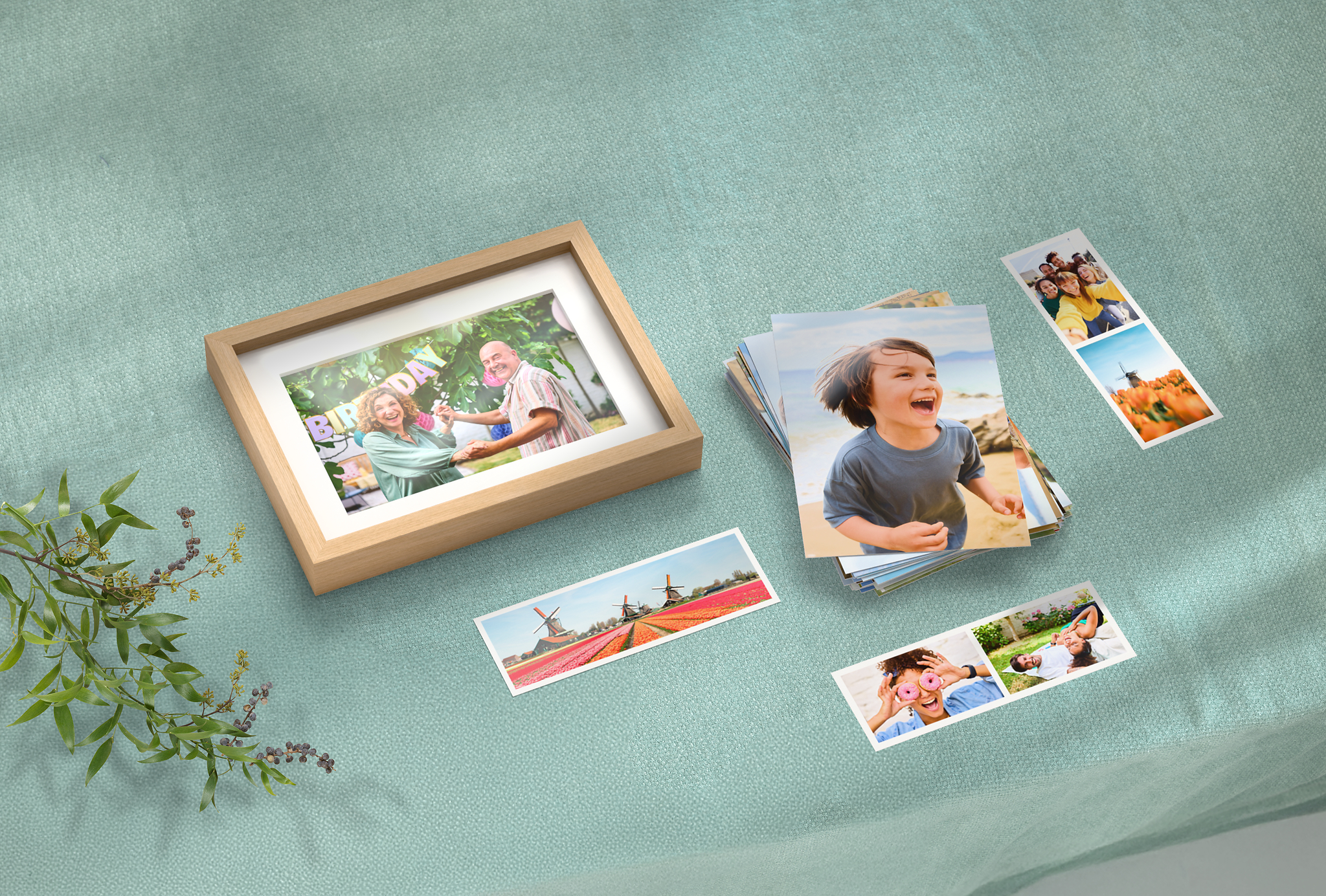 Foto im Eiche-Rahmen, Fotostreifen und ein Stapel klassische Fotoabzüge mit sommerlichen Motiven auf einem Tisch liegend