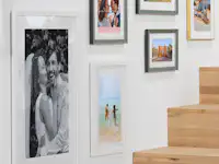 Bilder im Rahmen als Galeriewand gestalten Mehrere gerahmte Poster mit Familienfotos hängen an einer Wand.