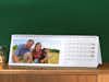 Calendrier de bureau horizontal Pixum avec une photo de famille devant un mur vert