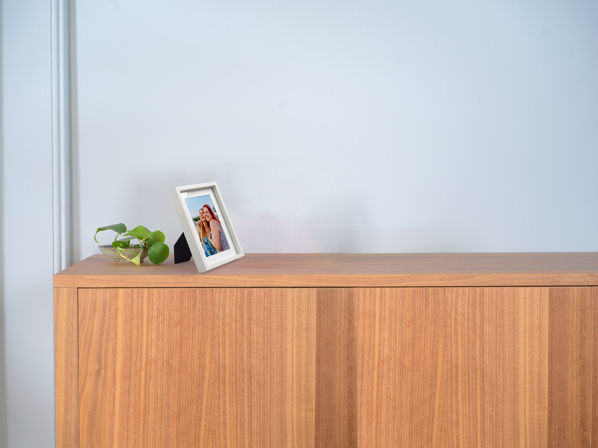 Foto van twee vrouwen die elkaar omhelzen in een witte houten lijst op een kastje