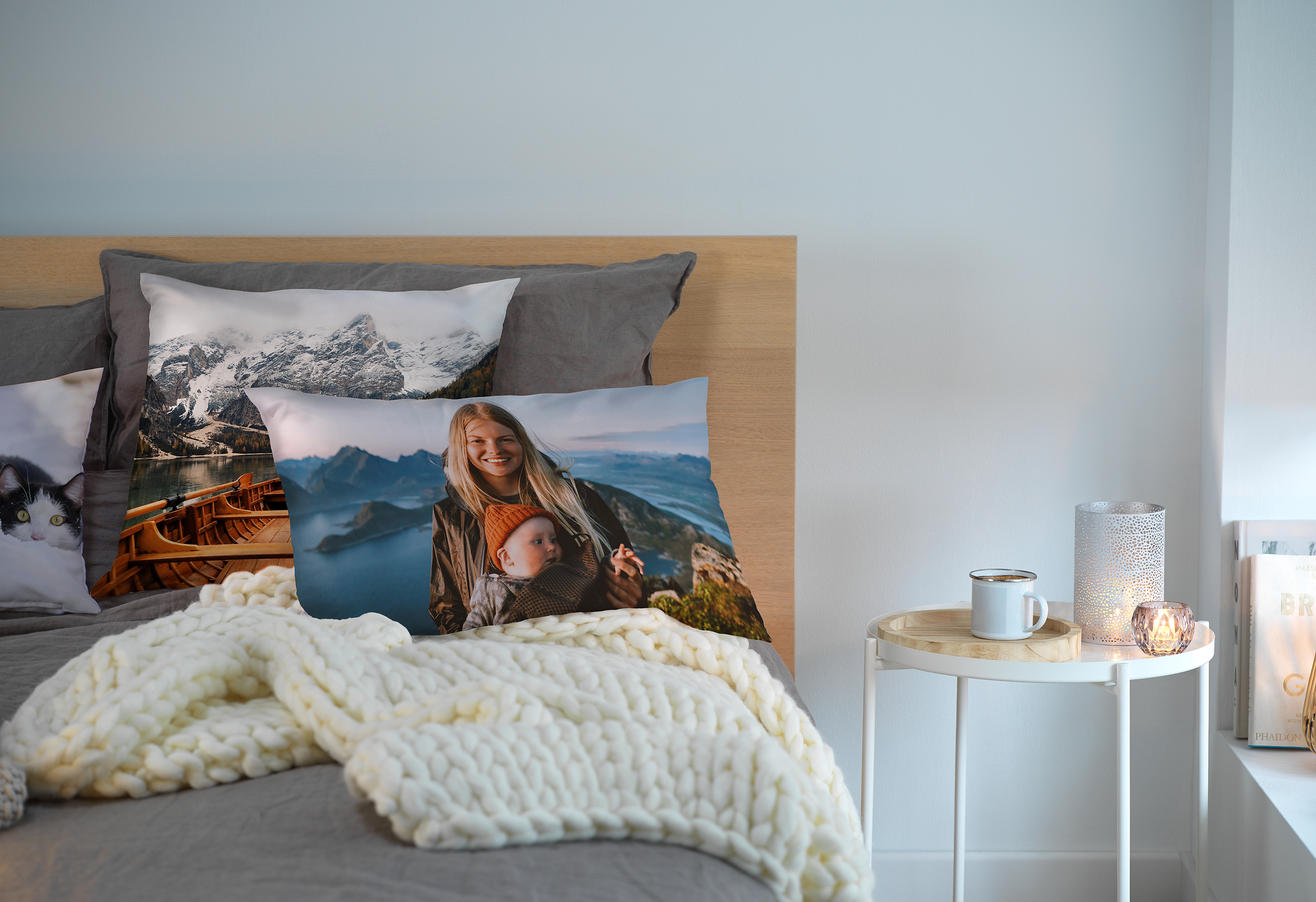 Fotokissen auf einem Bett  mit dem Bild von einer Mutter und ihrem Kind in den Bergen.