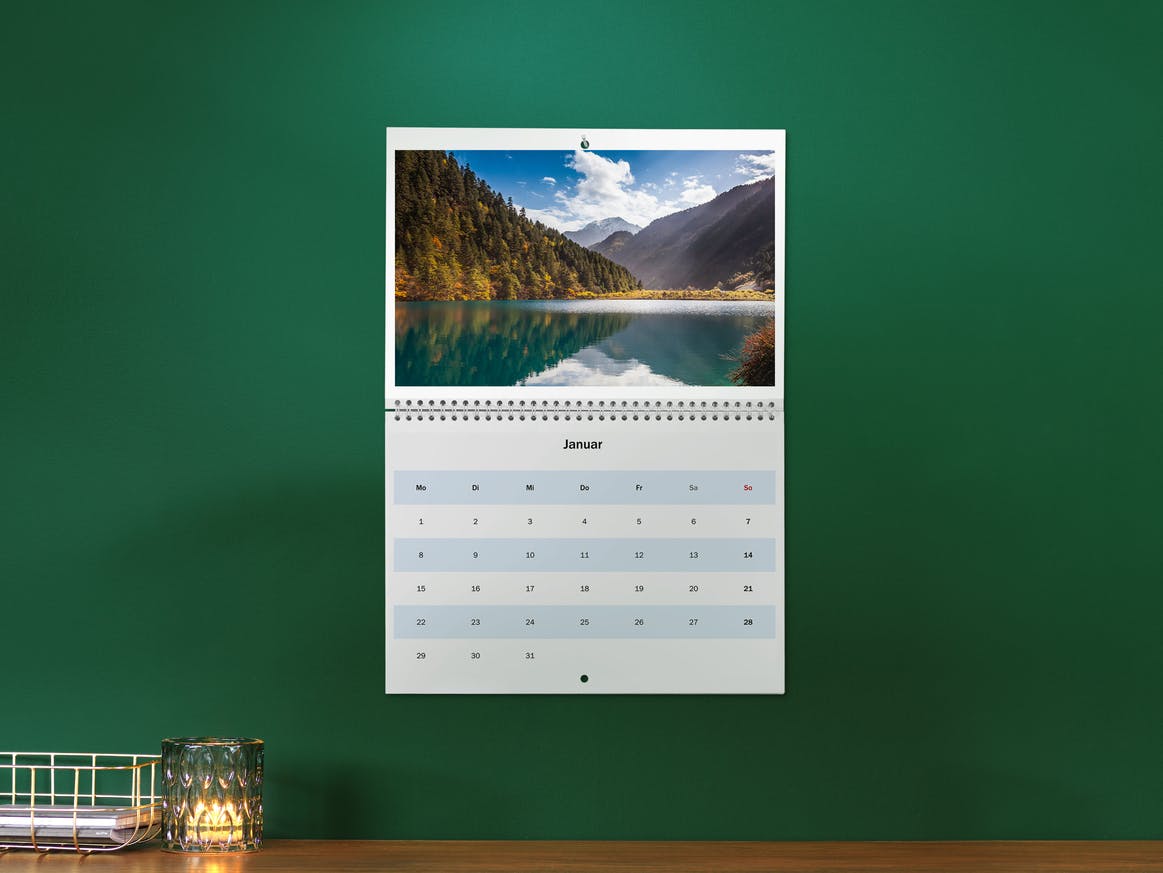 Calendario plegable A3 en una pared verde con la foto de un paisaje 