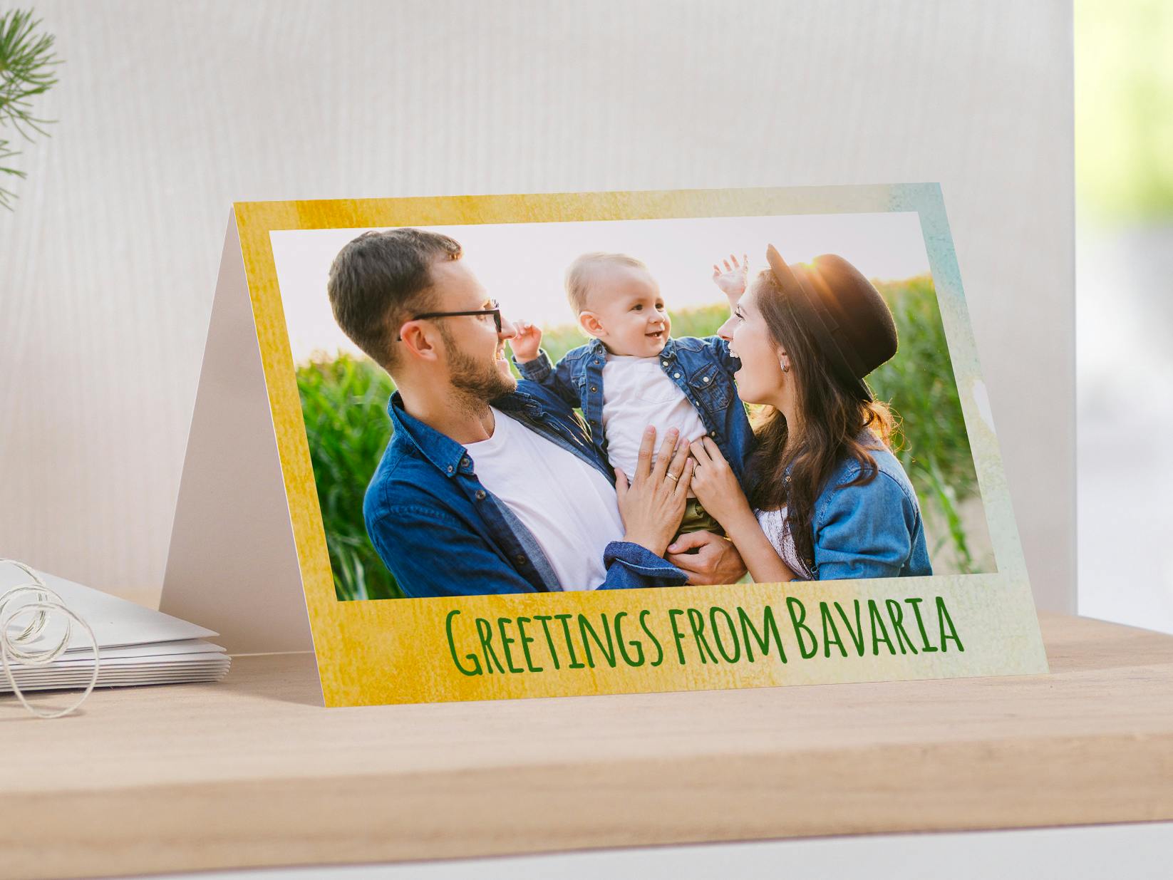 Aufgestellte Klappkarte mit dem Foto einer Familie und dem Text "Grüße aus Bayern"