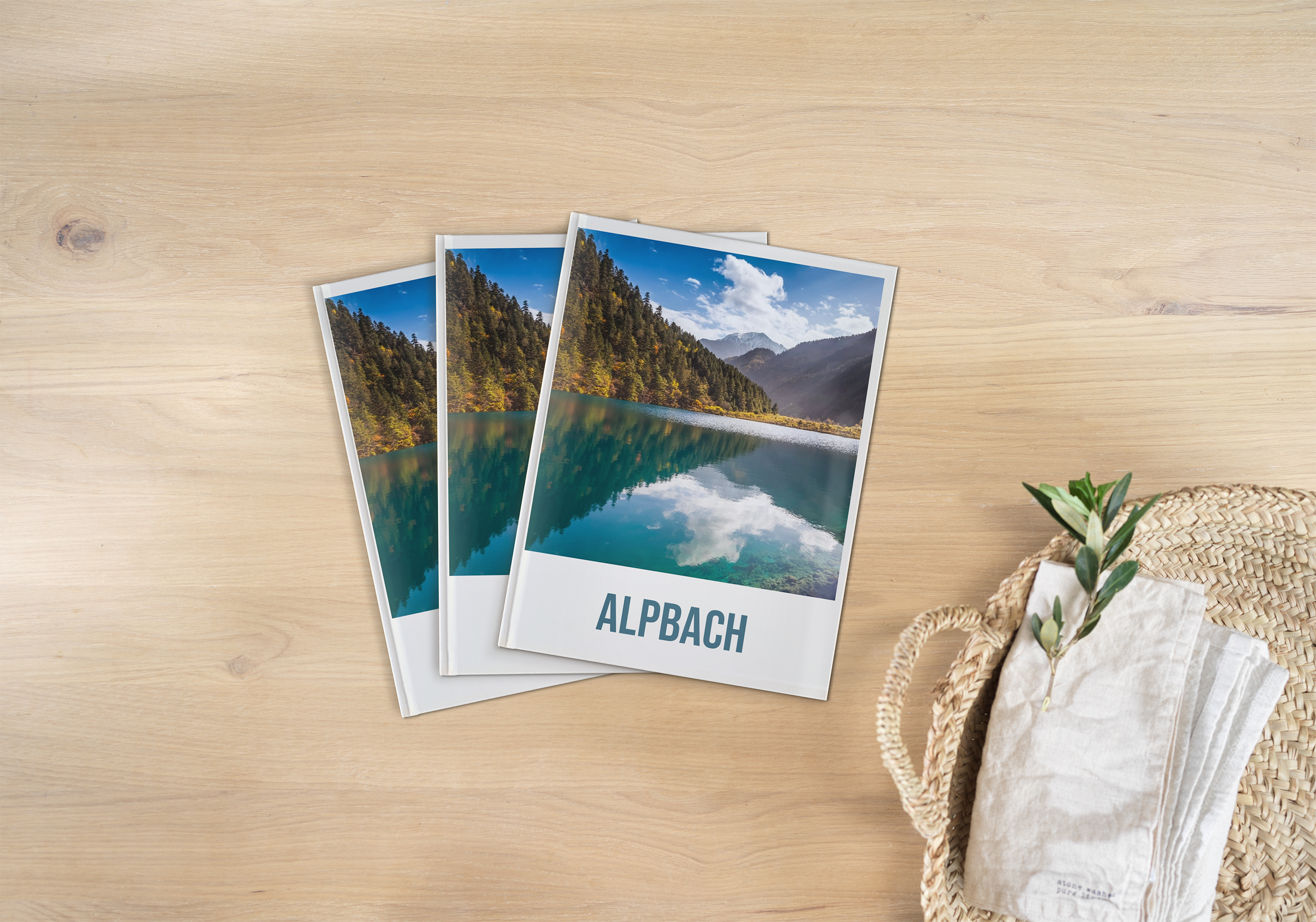 Drei gleiche Pixum Fotobücher im Hochformat, mit einem Landschaftsbild liegen auf neutralen Untergrund